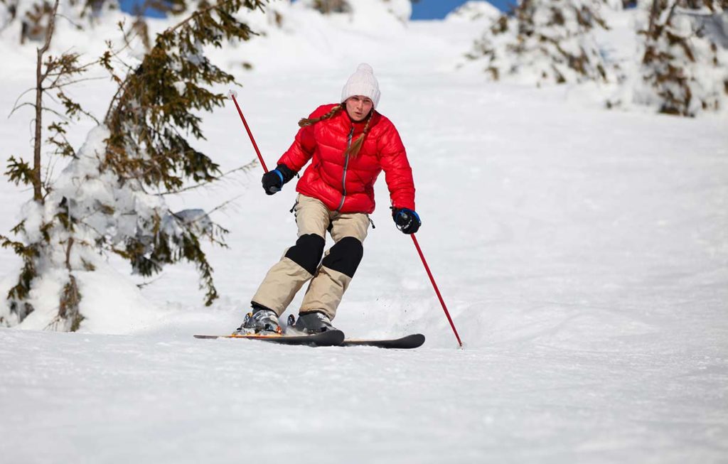 Woman in red jacket riding down North Dakota Skiing Slopes